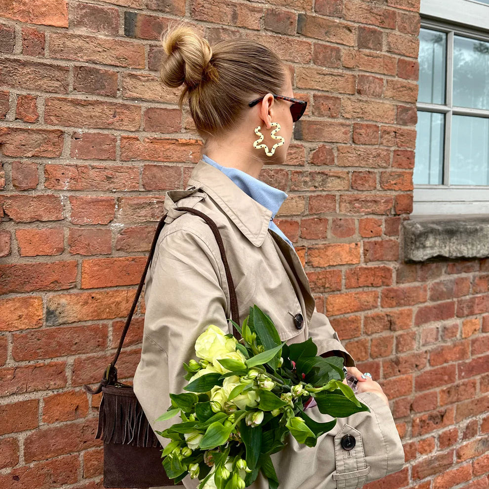 Woman holding flowers against a brick wall