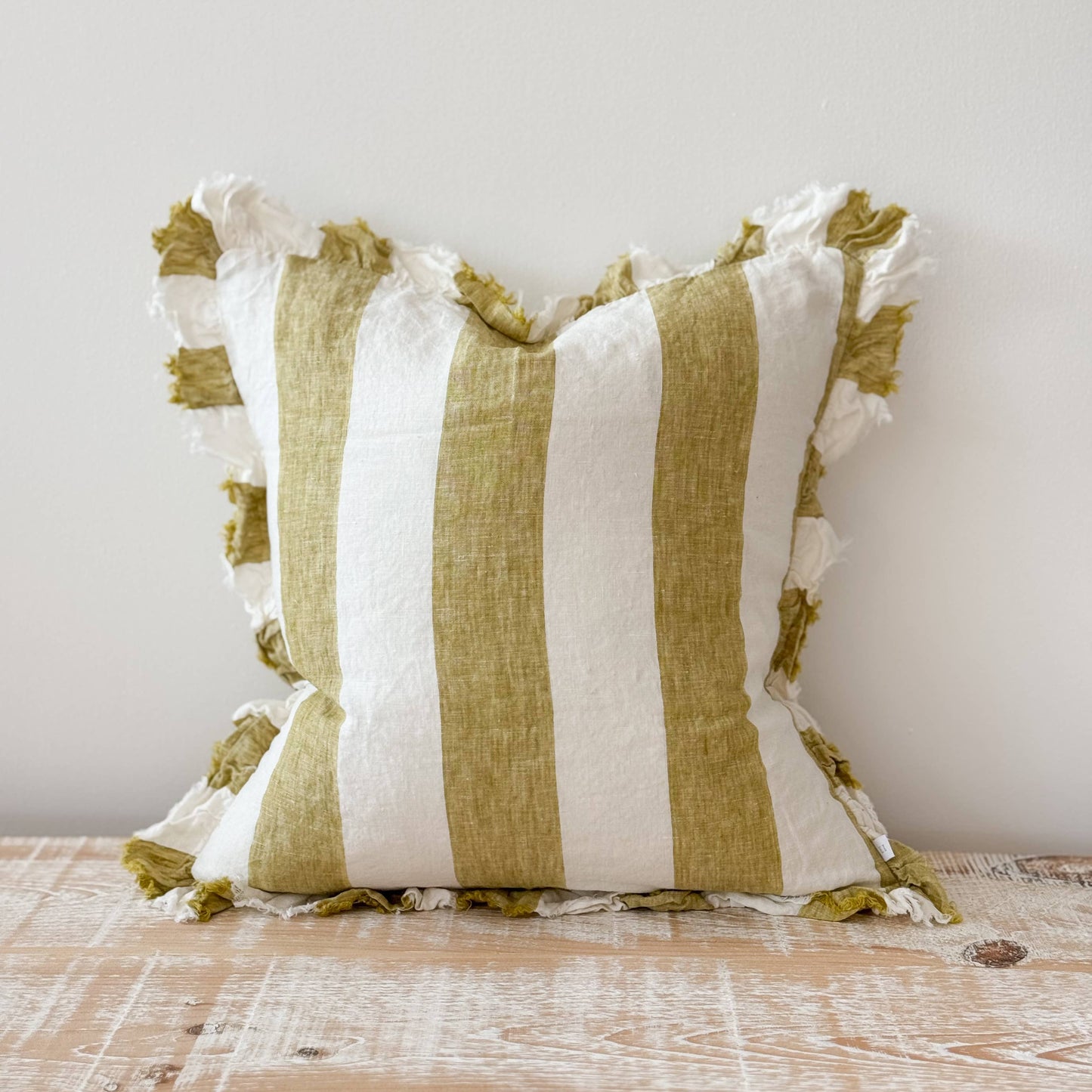 Striped pillow with green and white stripes on a wooden surface