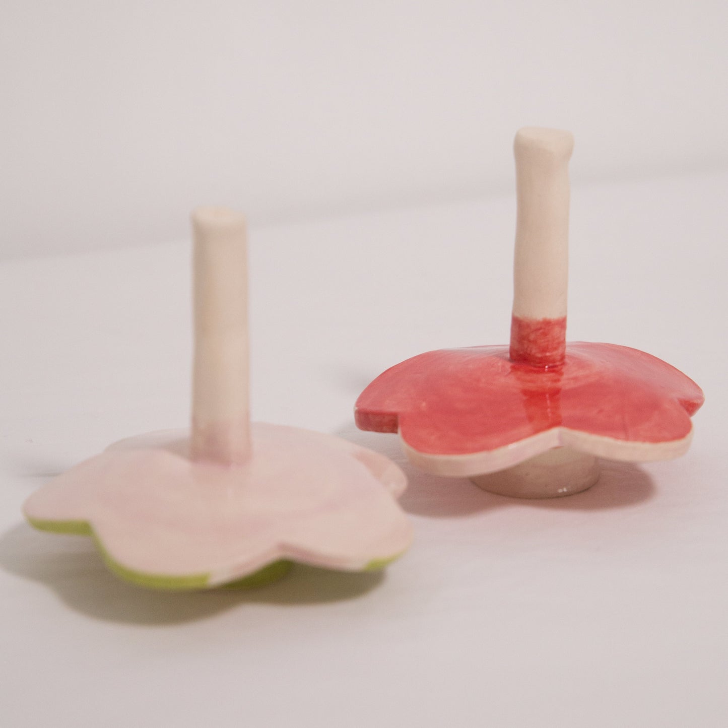 Two pink and green ceramic candle holders on a light gray background