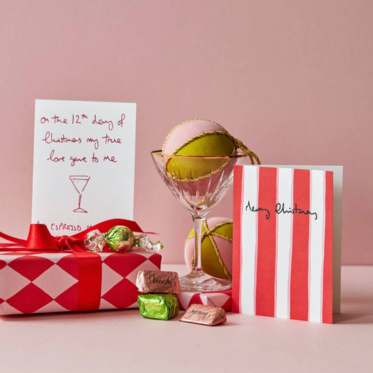 Gift box, cocktail with lime, and cards on a pink background