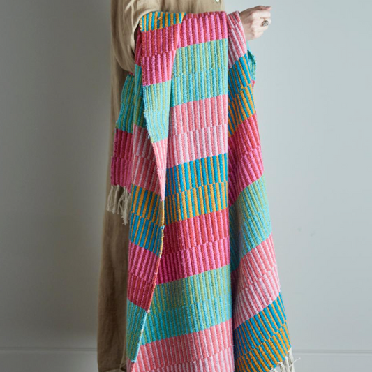 Colorful quilt draped over a person against a plain background