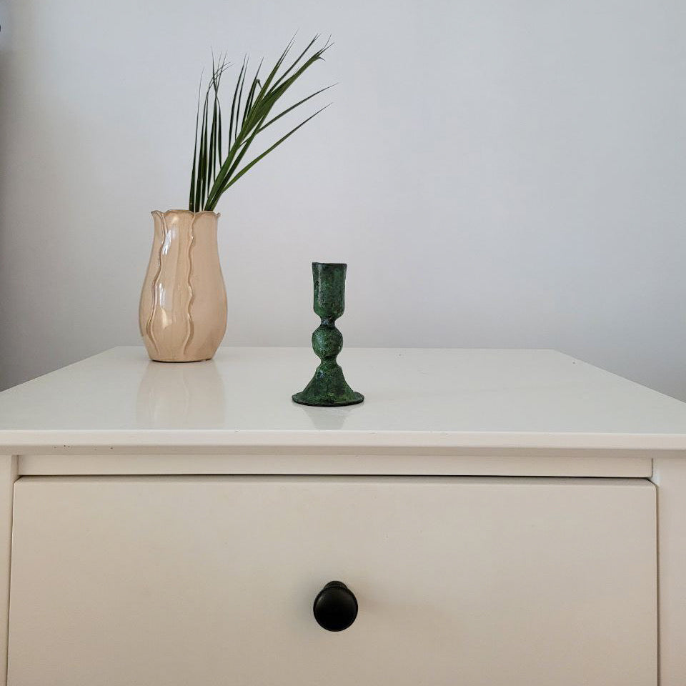 Displayed on a shelf with a vase, this green rustic candle holder from Bohemia Design