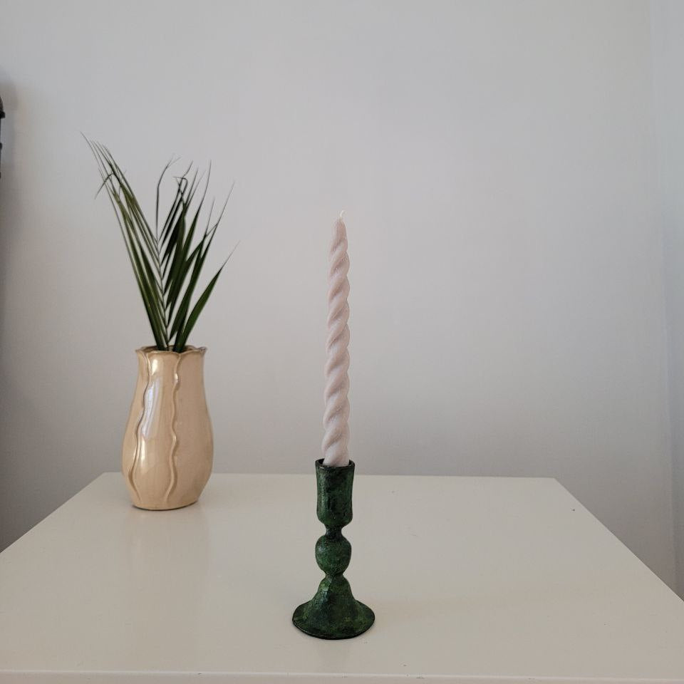 A collection of four Soie Soy Wax Twirl Taper Candles in various colors including green, gray, yellow, and white, displayed against a black background.