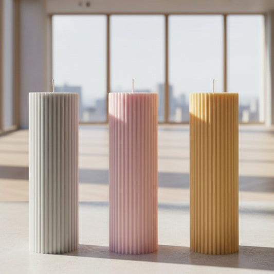 Three ribbed pillar candles in beige, pink, and orange colors, made from soy wax, displayed on a white surface against a neutral background.