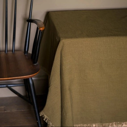 Green tablecloth on a wooden table with a black chair in the background.