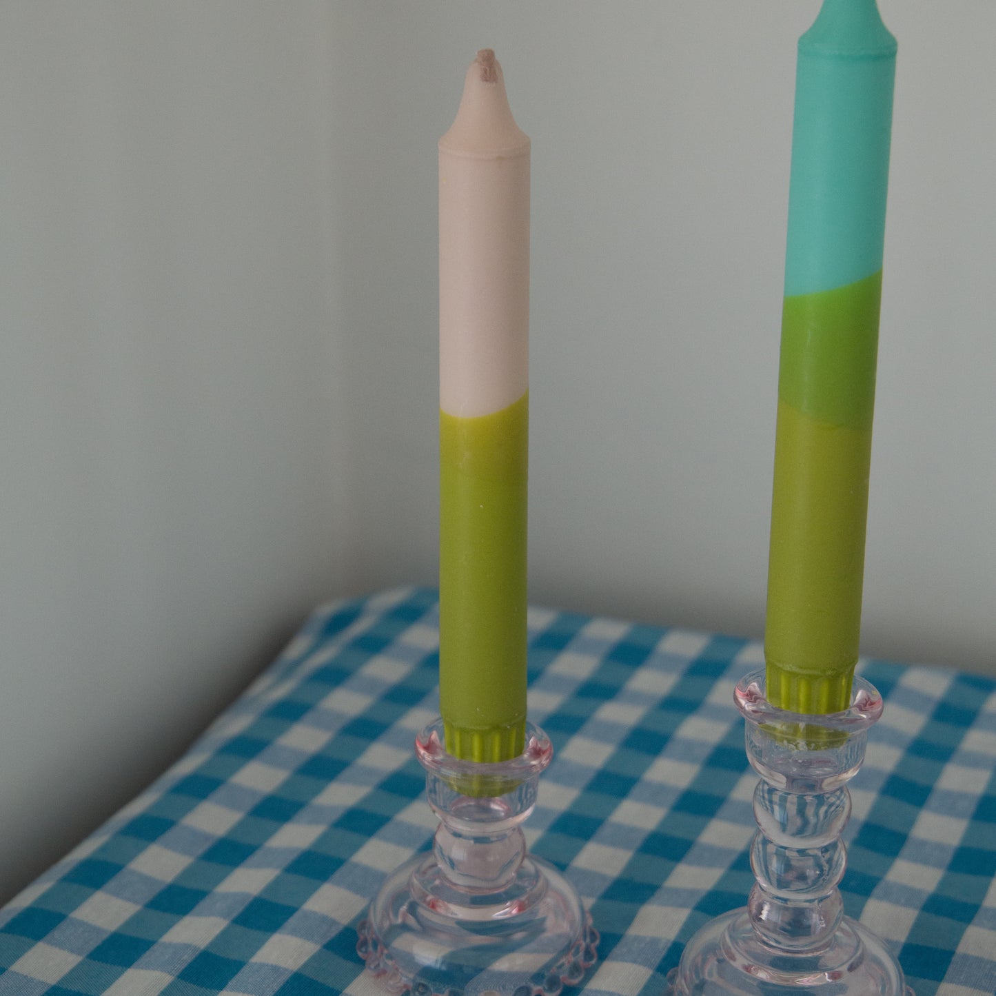 Nordtrice Earth colours tapered candles in pink and green displayed in pink glass candle holders