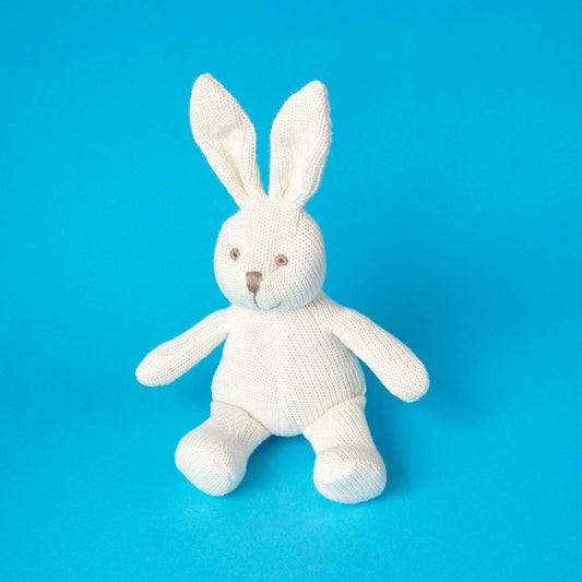 White knitted bunny toy on a blue background