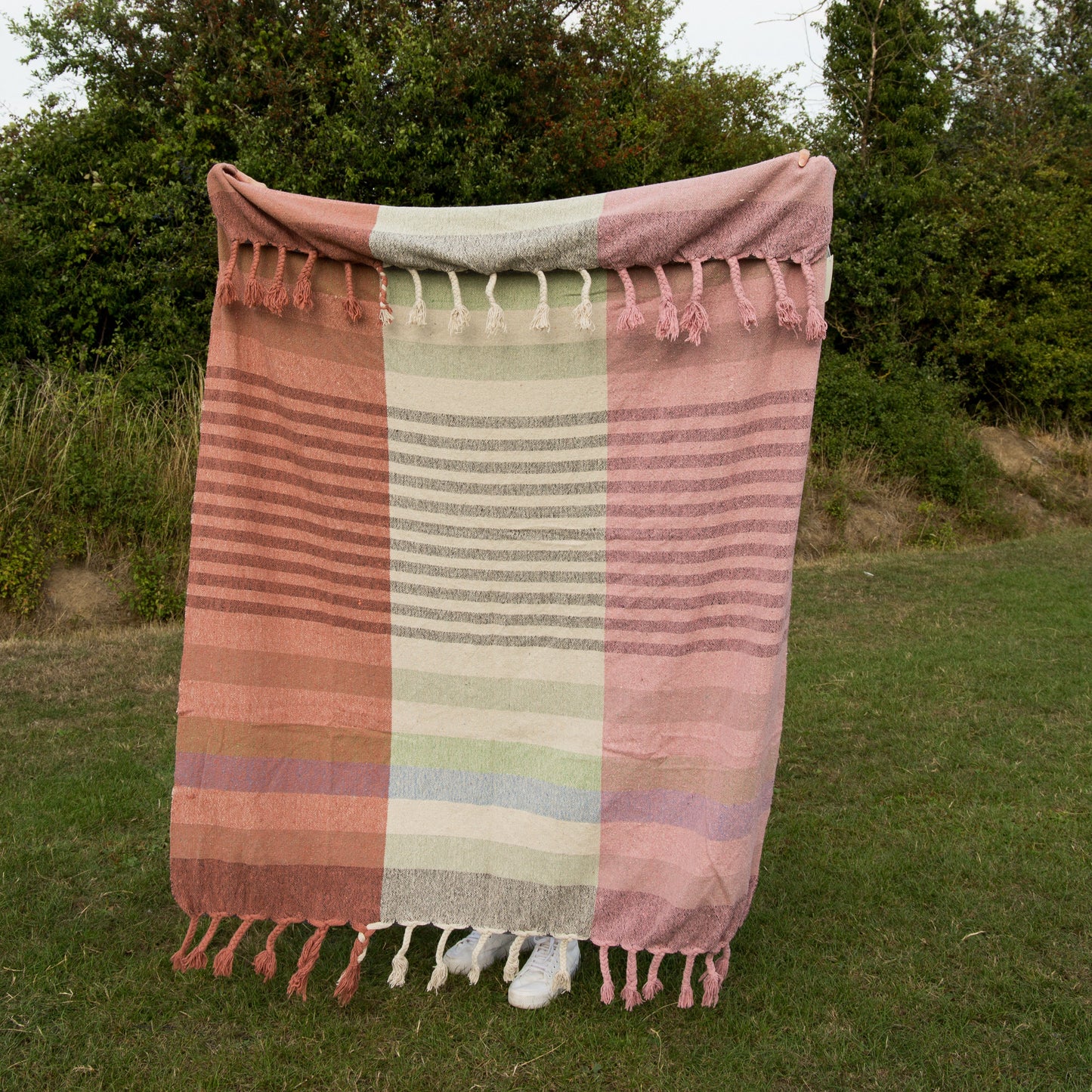 Colorful striped towel with tassels on a grassy field