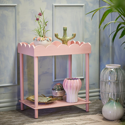 Pink side table with decorative items against a light blue wall.