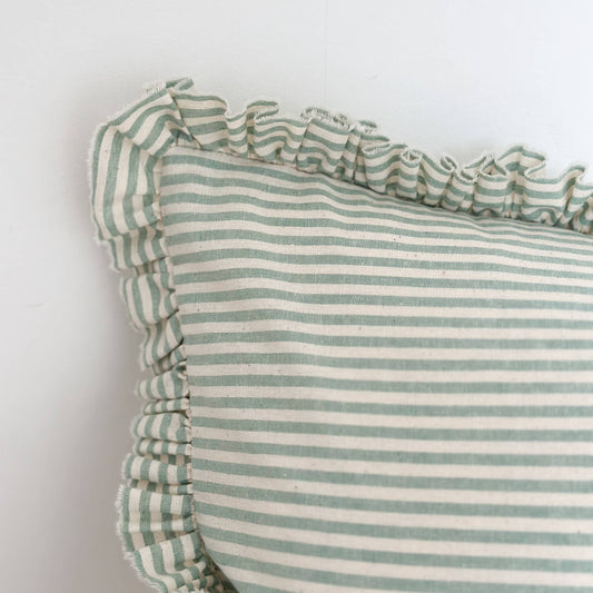 Green and white striped pillow with ruffled edges on a light background