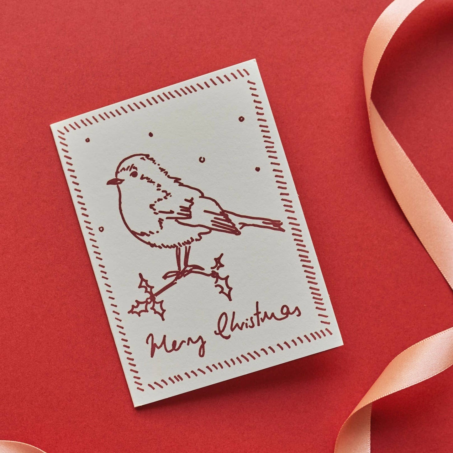 Christmas card with a bird illustration and 'Merry Christmas' text on a red background with a pink ribbon.