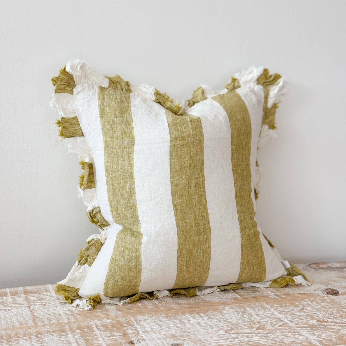 Striped pillow with green and white colors on a wooden surface.