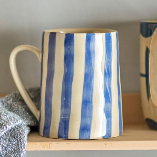 Mug with blue and white striped pattern on a wooden shelf