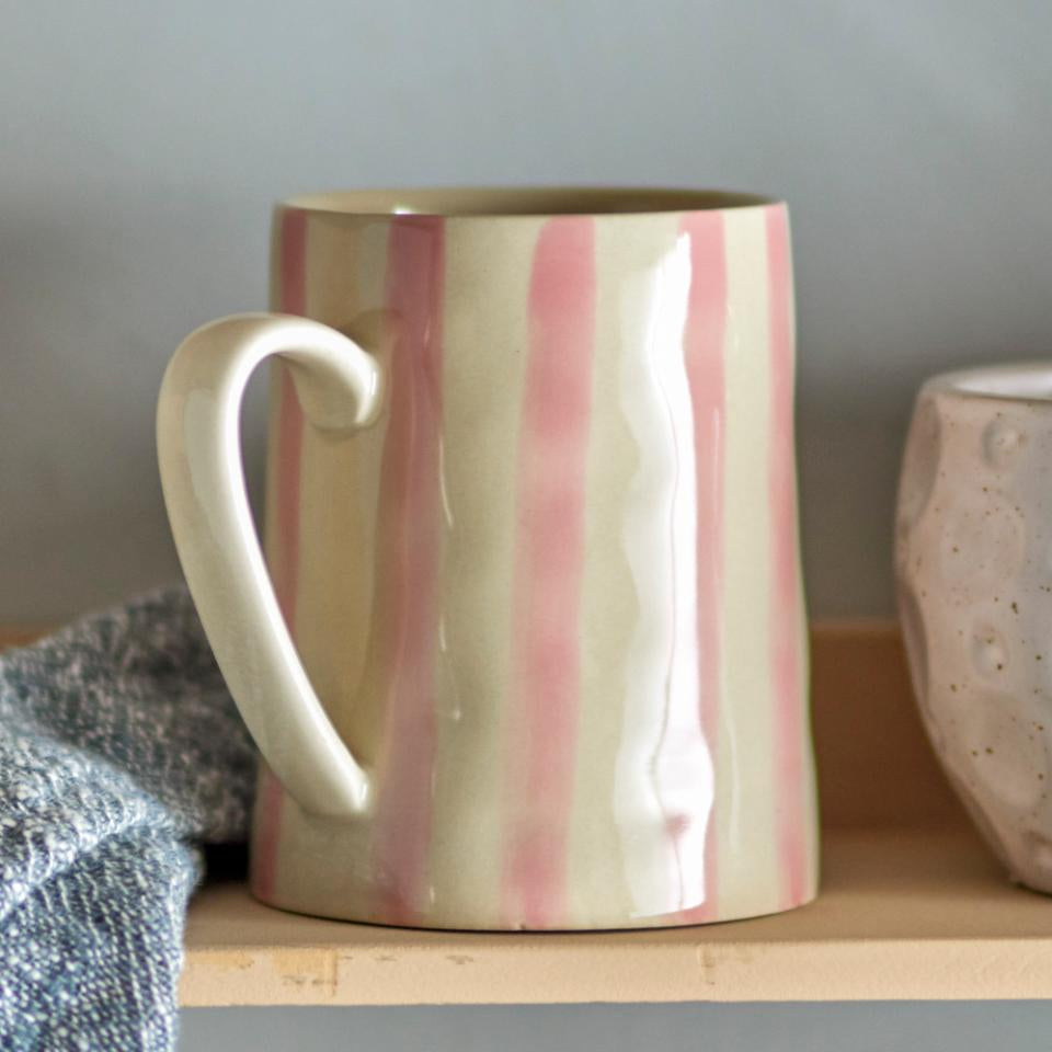 Striped ceramic mug on a wooden shelf with a neutral background