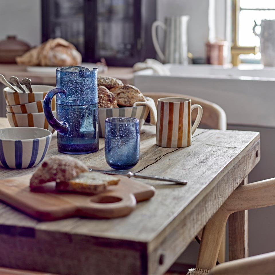 Kitchen counter with blue mugs, bread, and a cutting board.