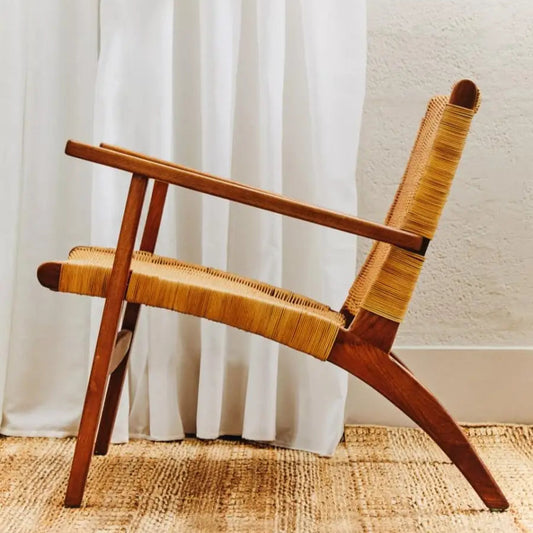 Wooden chair with woven backrest in front of white curtains
