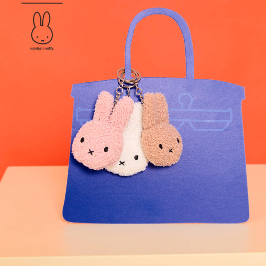 Blue handbag with three fluffy keychains on an orange background, featuring the Bon Ton Toys brand.