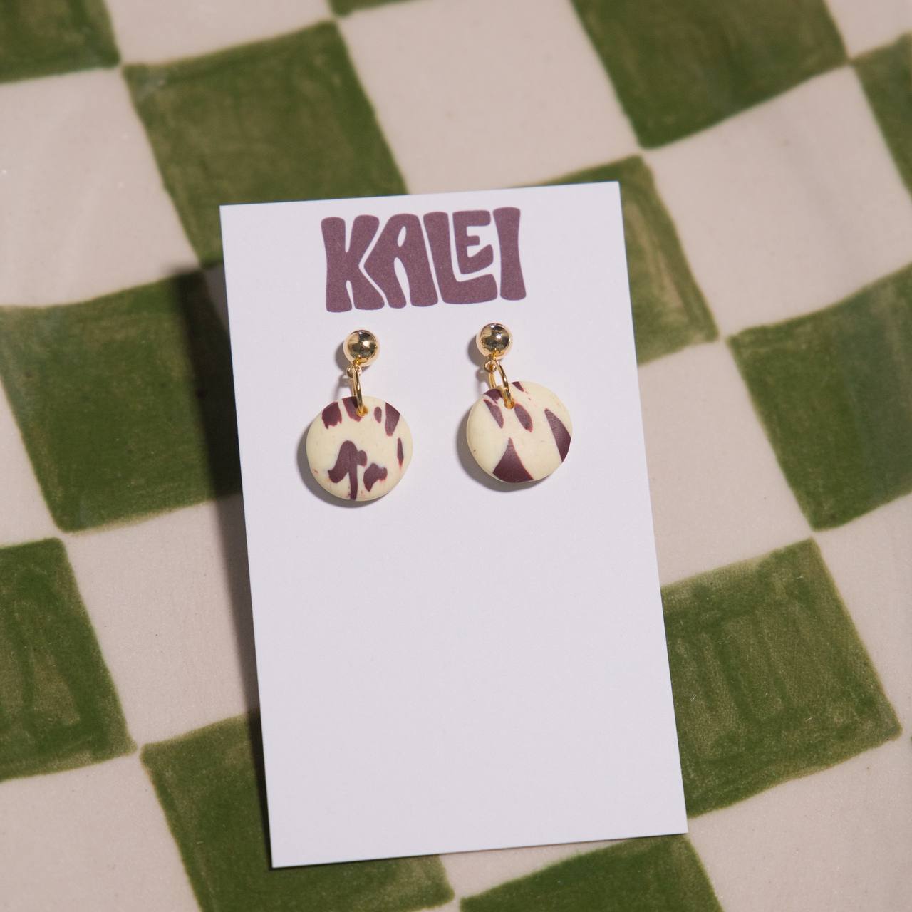 Pair of earrings on a 'KALEI' branded card against a checkered background