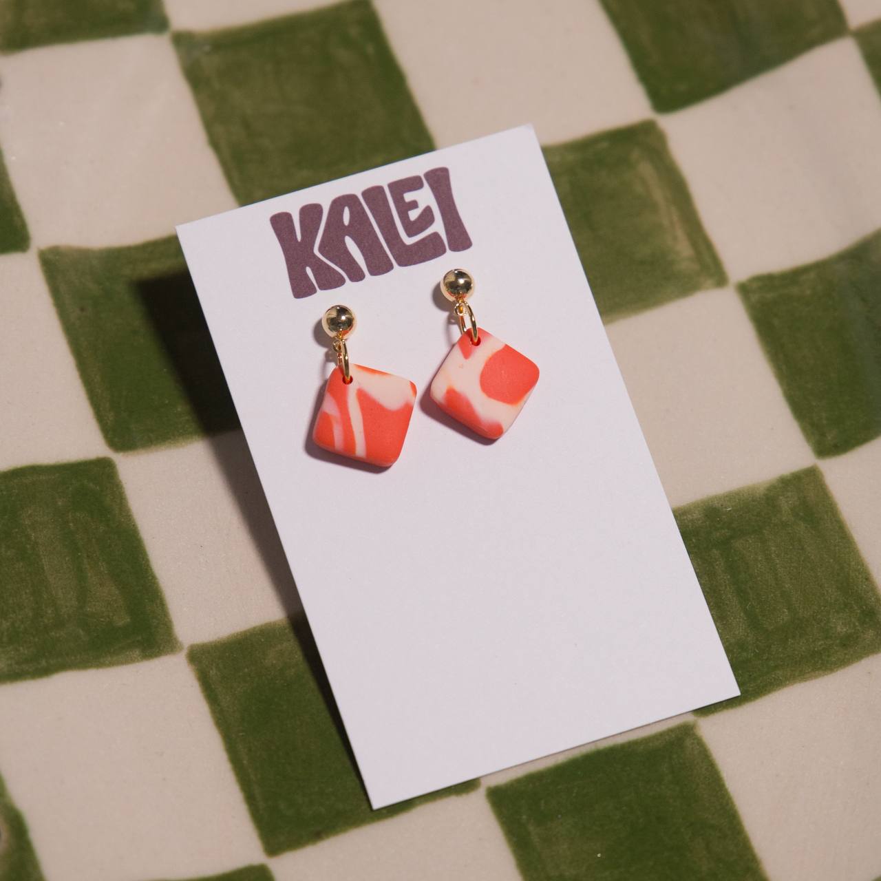 Pair of earrings on a KALEI branded card against a checkered background