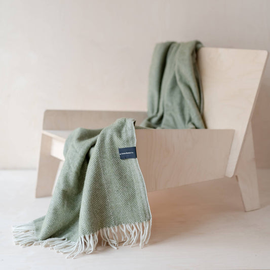 TBCo Olive Knee Blanket draped over a chair.