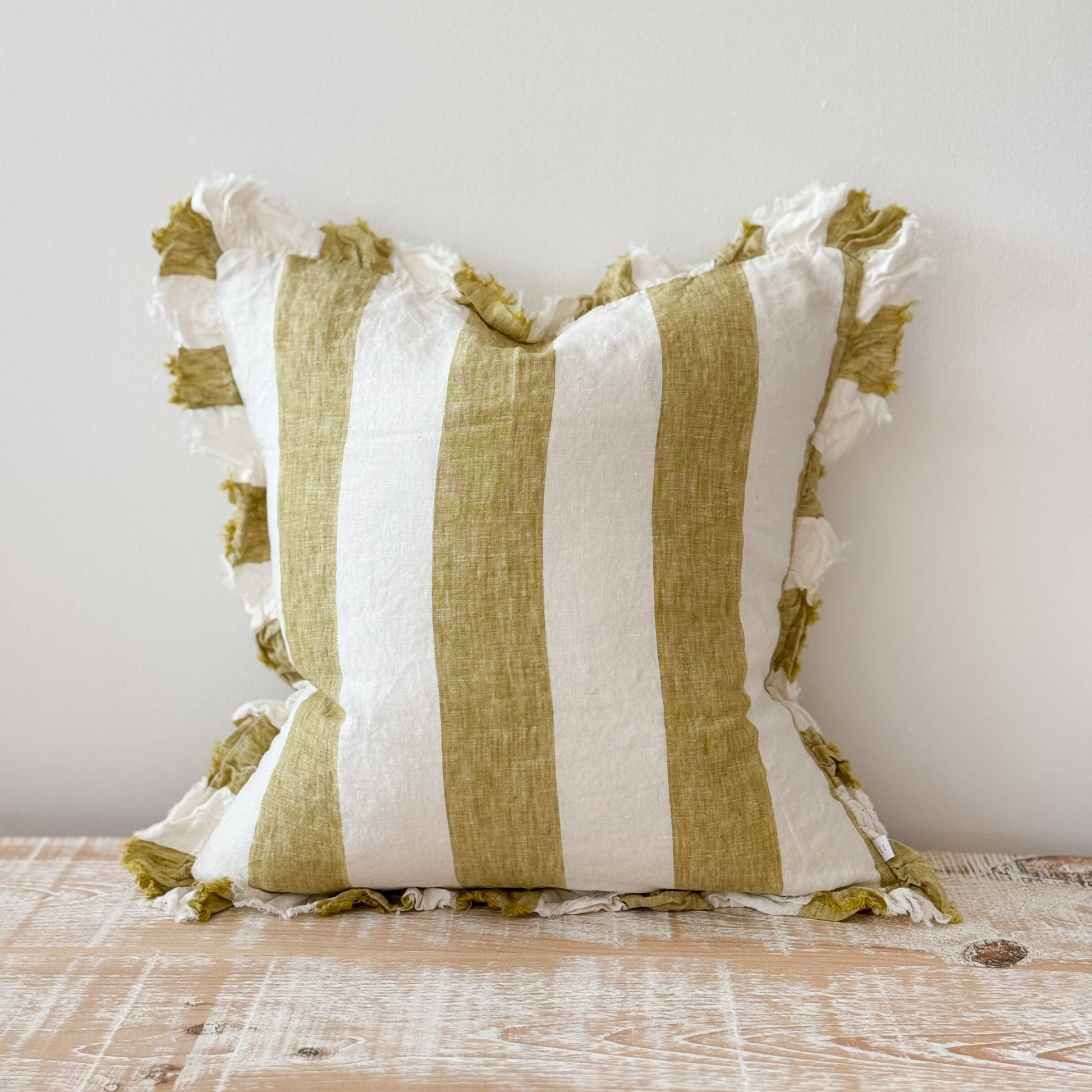 Striped pillow with green and white stripes on a wooden surface