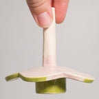 Hand holding a small ceramic or porcelain object with a green base on a plain background