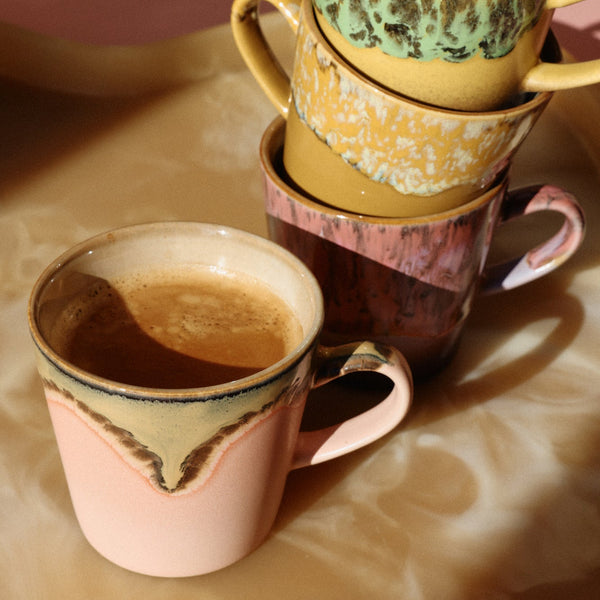 Stack of ceramic coffee cups with different patterns on a wooden surface