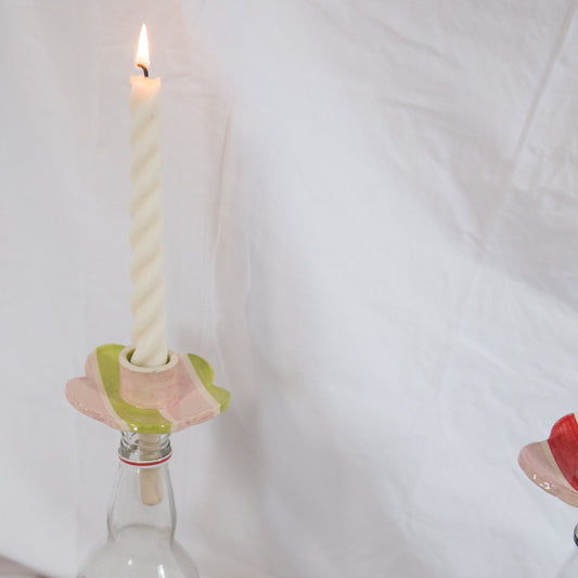 Candle in a glass bottle with decorative holder on a white background