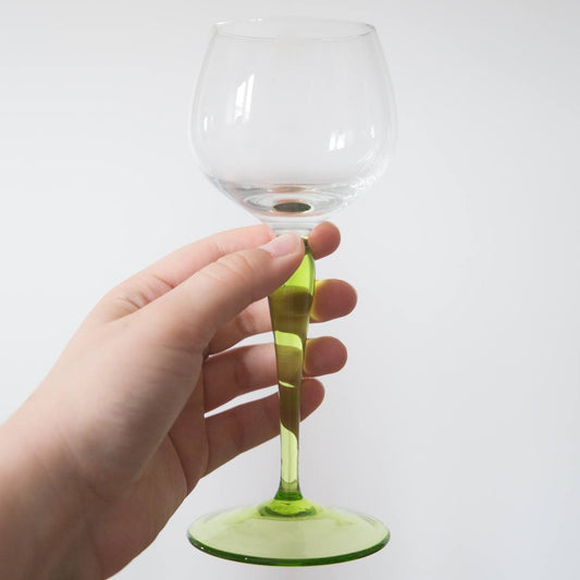 Hand holding a wine glass with a green stem against a white background