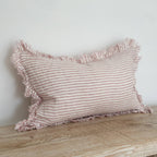Striped pillow with ruffled edges on a wooden surface against a white wall