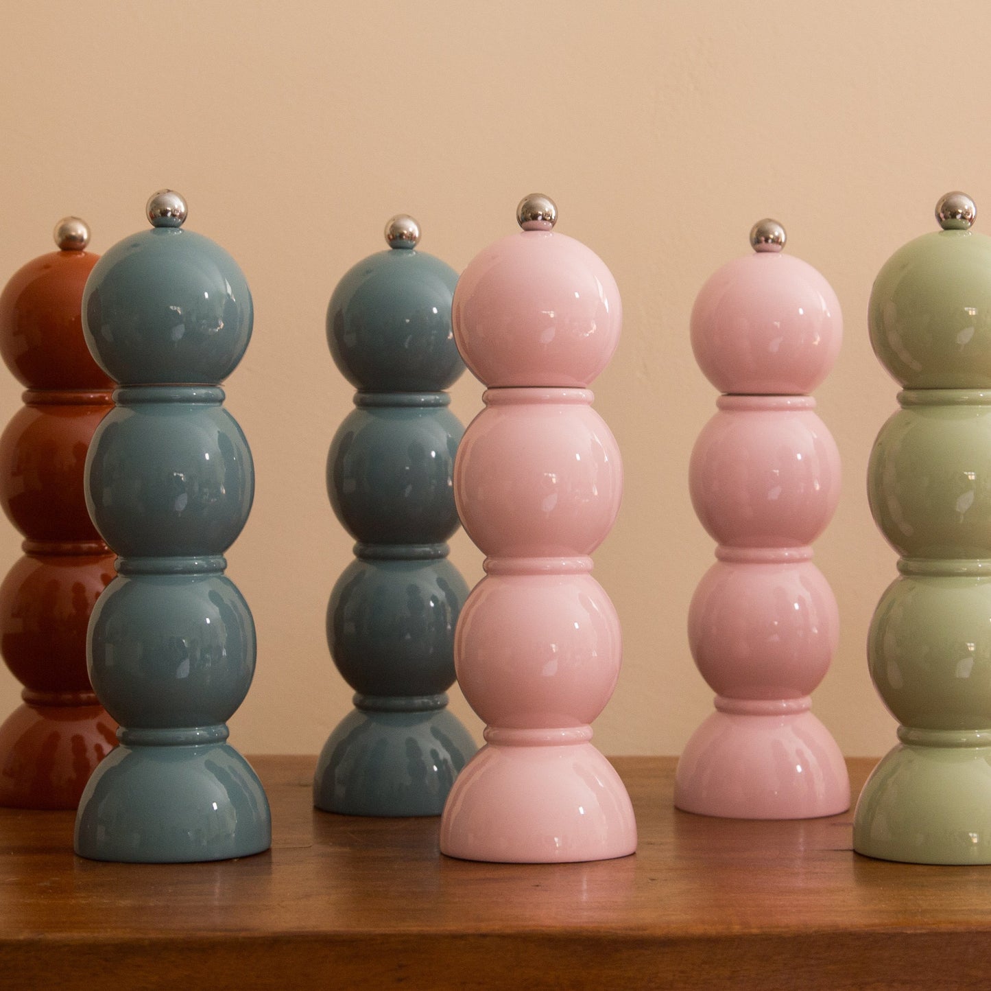 Set of colorful ceramic salt and pepper shakers on a wooden surface with a beige background.