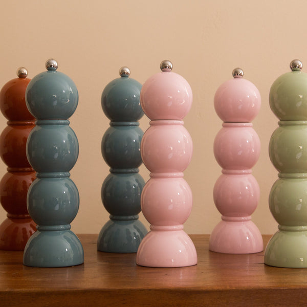 Set of colorful ceramic salt and pepper shakers on a wooden surface with a beige background.