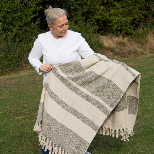 Woman holding a striped blanket outdoors in a natural setting