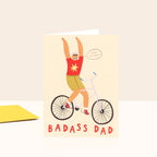 Card with illustration of a father on a bike and 'Badass Dad' text on a beige background