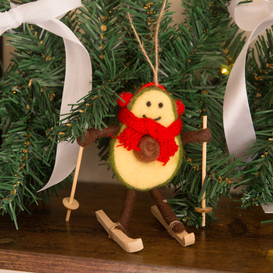 Decorative ornament resembling a skier with a red scarf against a Christmas wreath background