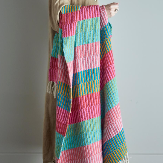 Colorful quilt draped over a person against a plain background