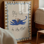 Decorative wall art with a tiger and child illustration and text 'Fly Me to the Moon' in a room setting.