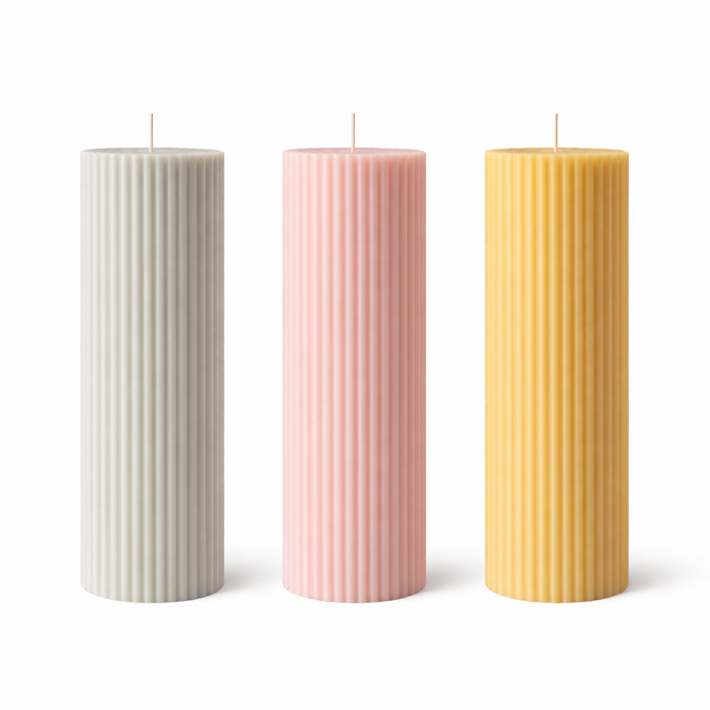 Three ribbed pillar candles in beige, pink, and orange colors, made from soy wax, displayed on a white surface against a neutral background.