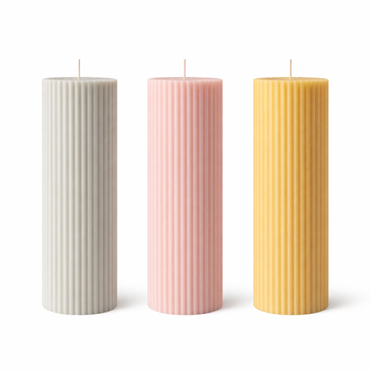 Three ribbed pillar candles in beige, pink, and orange colors, made from soy wax, displayed on a white surface against a neutral background.