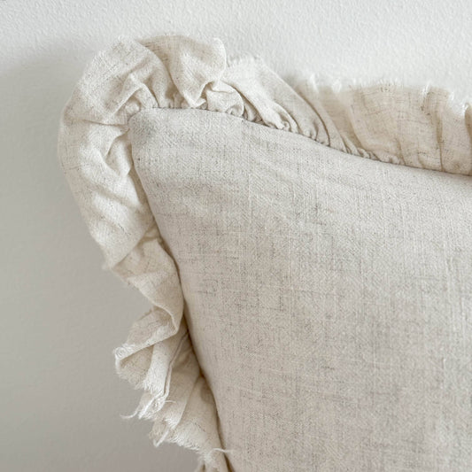 Ellenvale Grace Linen Blend Cushion Cover in Sand displaying the corner detail of the cushion against a white wall.