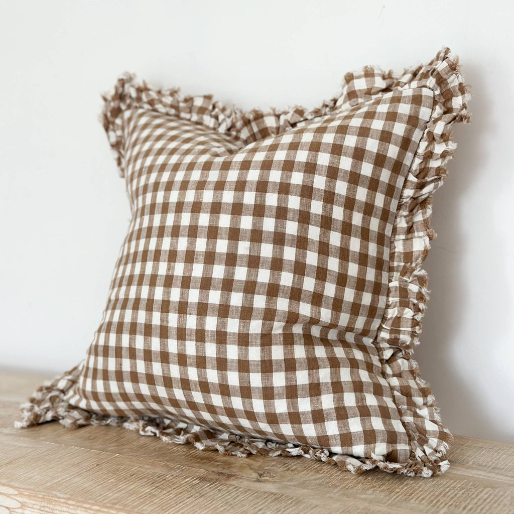 Ellenvale Ruffled Edged Linen Cushion Cover in Brown Gingham displayed on a bench against a white wall.