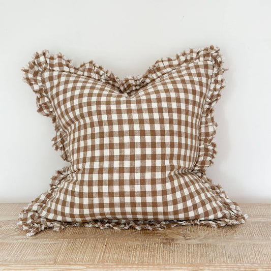 Ellenvale Ruffled Edged Linen Cushion Cover in Brown Gingham displayed on a bench against a white wall.