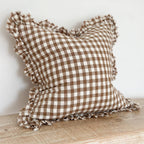 Ellenvale Ruffled Edged Linen Cushion Cover in Brown Gingham displayed on a bench against a white wall.