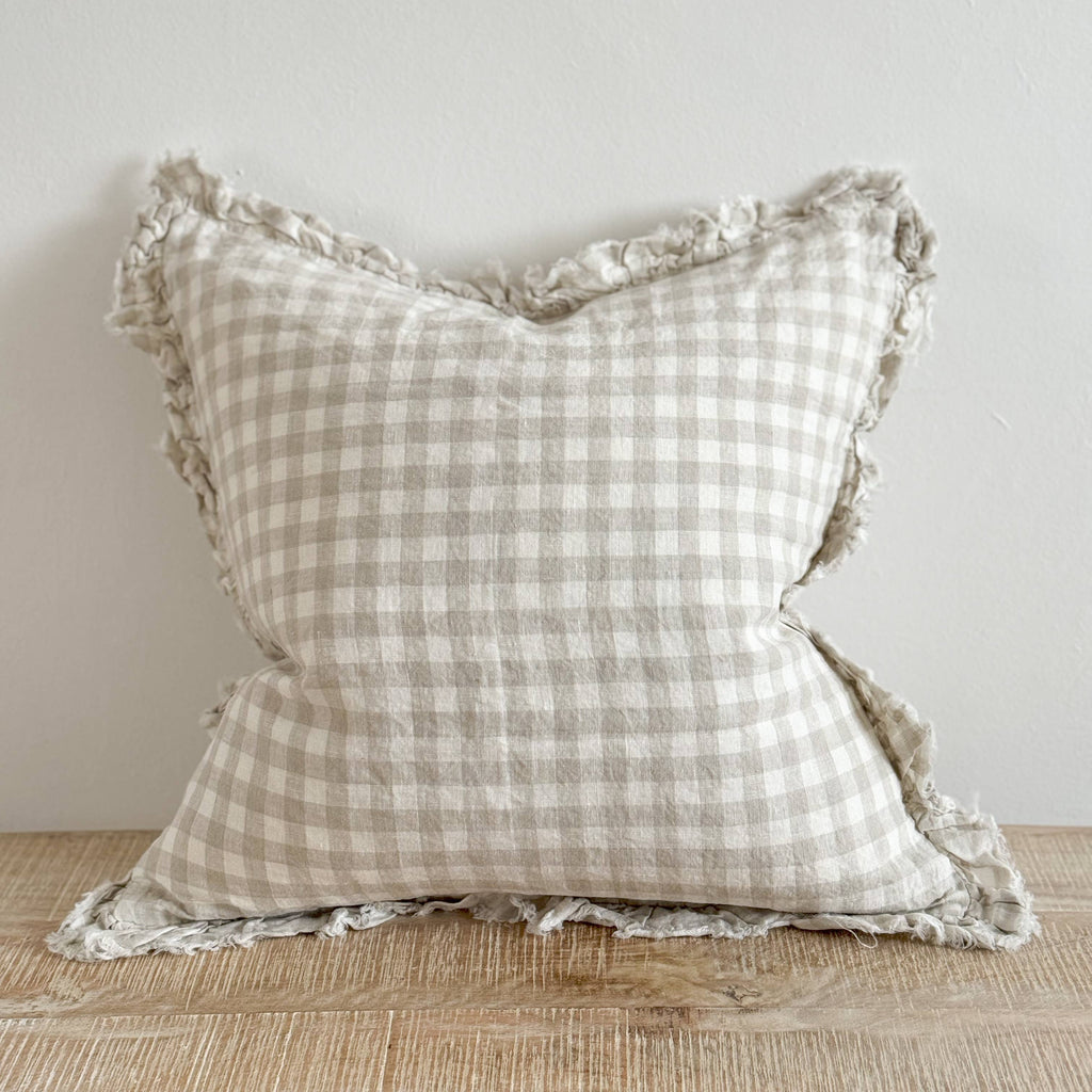 Ellenvale Ruffled Edged Linen Cushion Cover in Natural Gingham displayed on a bench against a white wall.