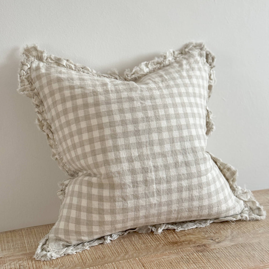 Ellenvale Ruffled Edged Linen Cushion Cover in Natural Gingham displayed on a bench against a white wall.