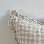 Ellenvale Ruffled Edged Linen Cushion Cover in Natural Gingham displaying the corner edge of the cushion against a white wall.