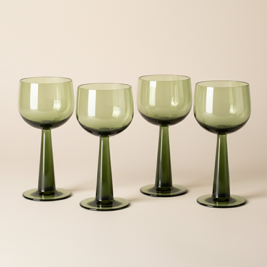 Four green wine glasses on a beige background