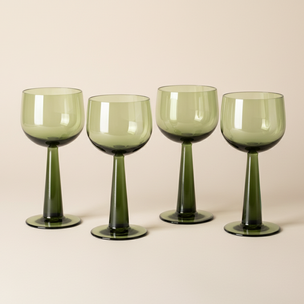 Four green wine glasses on a beige background