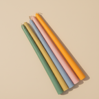 Set of five pastel-colored candles on a beige background