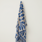 Blue and beige patterned blanket with fringes on a white background